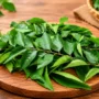 Fresh Green Curry Leaves (Karivepaku / Karuveppilai) Arranged on a Wooden Board